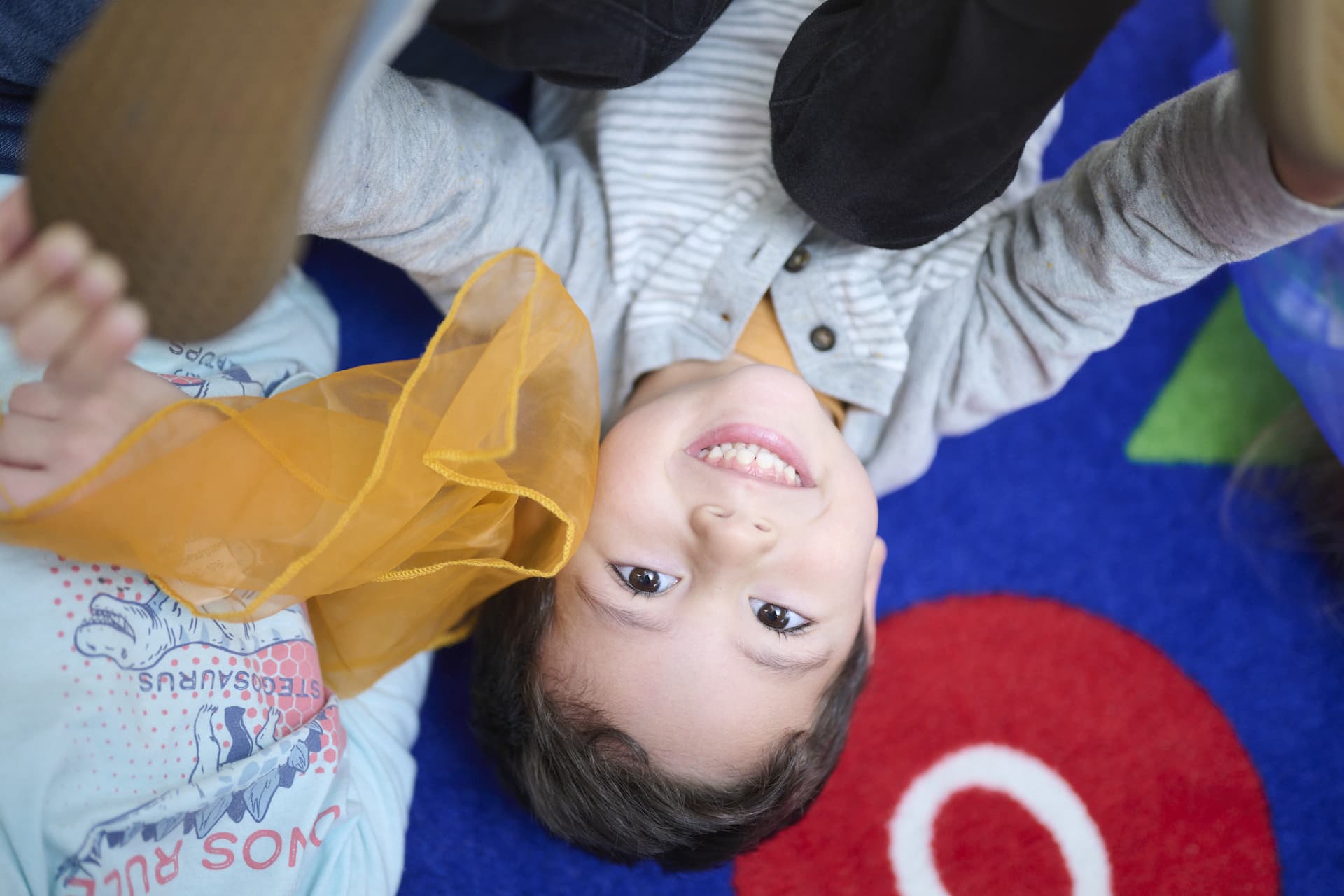 A young boy playing to the floor looking up at camera