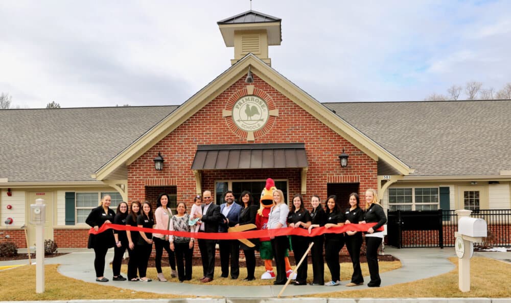 people standing outside cutting a ribbon for the school opening