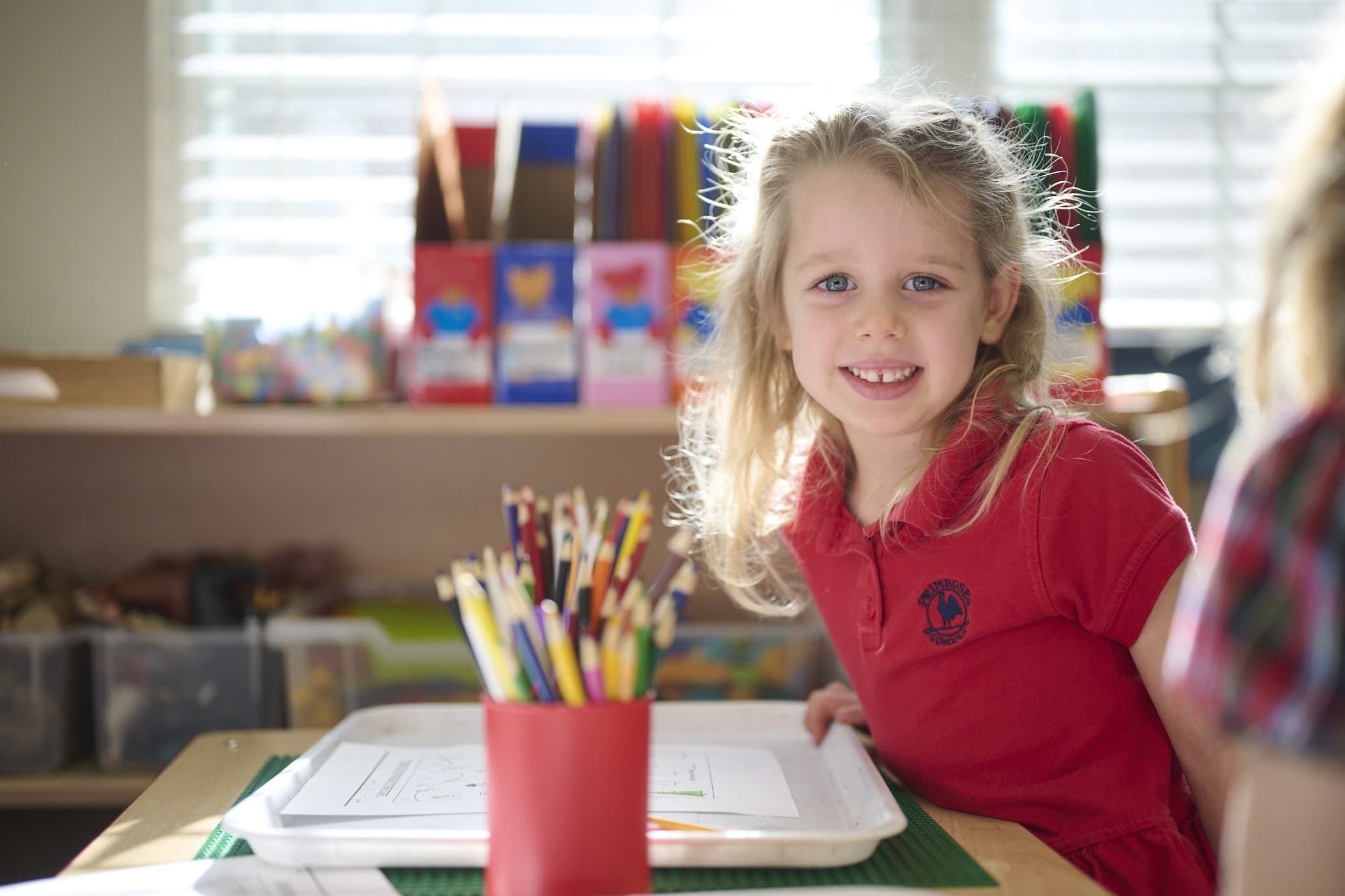 child smiling with school supplies on table