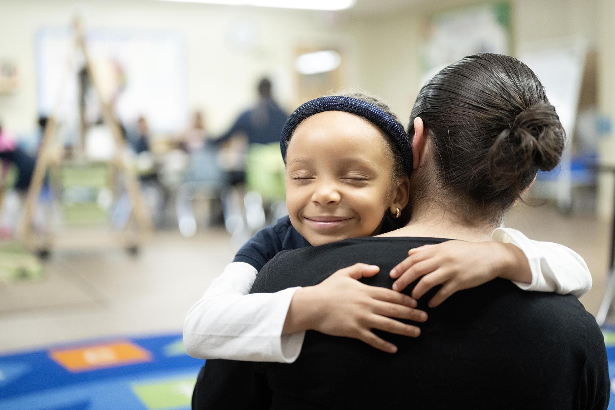 prekindergarten child hugging teacher